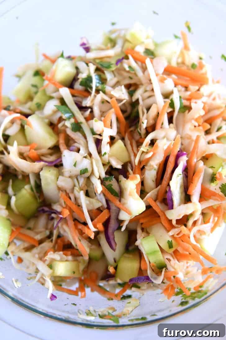 Glass bowl with shredded cabbage, lime juice, and chopped cilantro for the quick slaw.