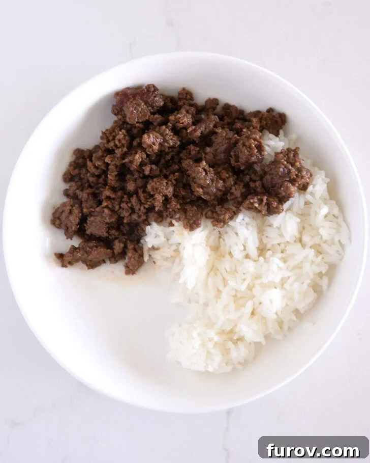 White bowl with a base of fluffy white rice topped with a generous serving of Korean ground beef.