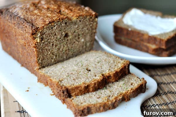 A rustic image displaying a freshly baked loaf of zucchini bread with two perfectly cut slices, arranged invitingly on a wooden cutting board.