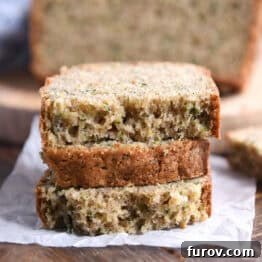 Three half slices of zucchini bread stacked on a piece of parchment paper, highlighting the moist texture and inviting aroma.