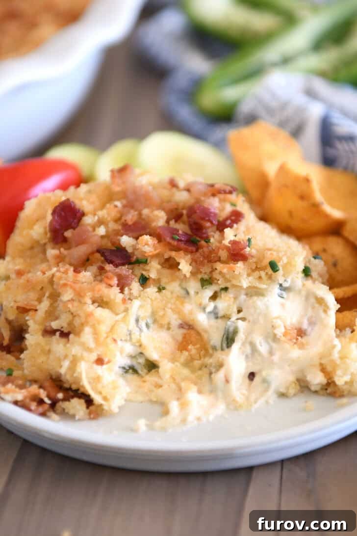 Creamy cheesy bacon dip on gray plate with chips and veggies.