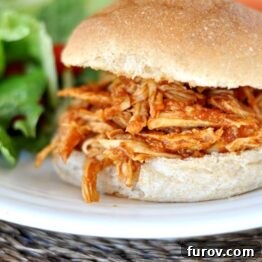 Delicious BBQ Pulled Chicken Sandwich on a whole wheat bun, garnished with fresh parsley.