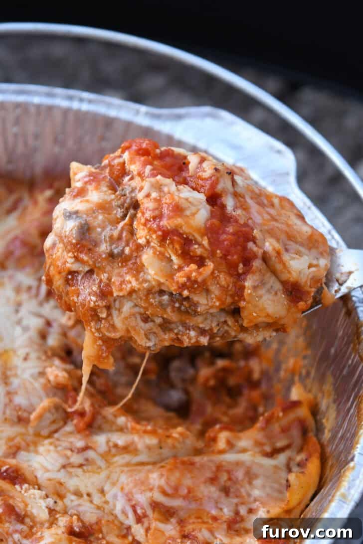 Ultimate Dutch Oven Lasagna 2 A serving spoon lifting a generous portion of cheesy Dutch oven lasagna from the pot, showcasing its layers.