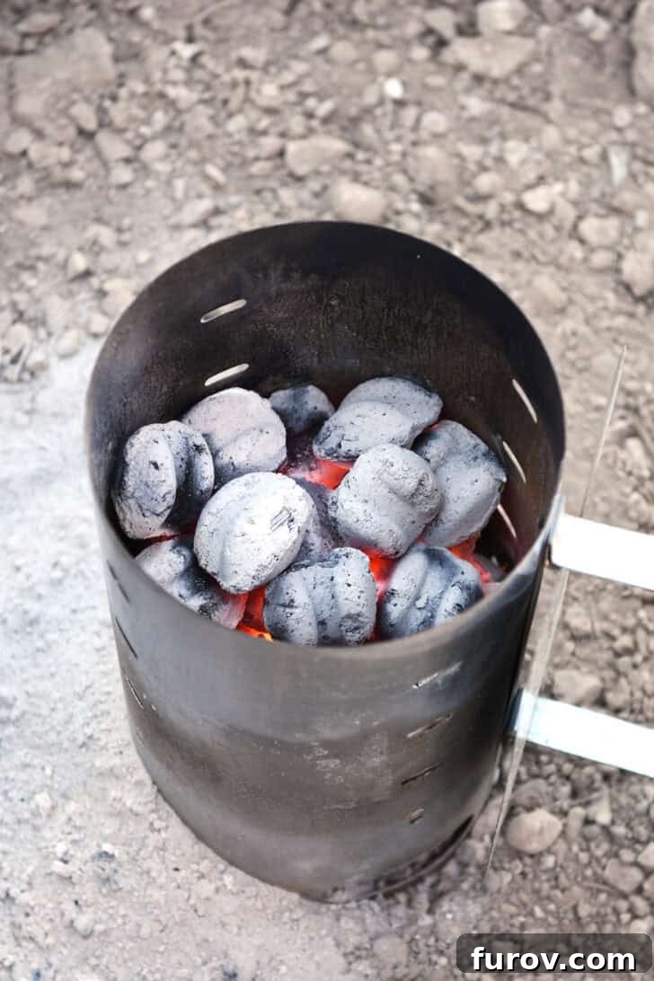 Ultimate Dutch Oven Lasagna 12 A chimney starter brimming with glowing, hot charcoal briquettes, covered in ash and ready for cooking.