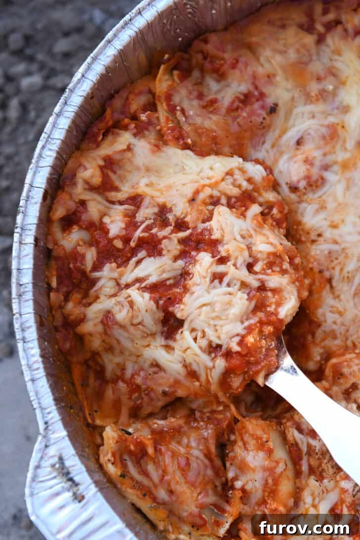 Ultimate Dutch Oven Lasagna 17 A serving spoon gracefully scooping a hot, cheesy portion of Dutch oven lasagna from the pot.
