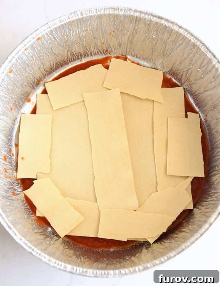 Ultimate Dutch Oven Lasagna 6 Top-down view of broken lasagna noodles meticulously arranged in a Dutch oven liner.