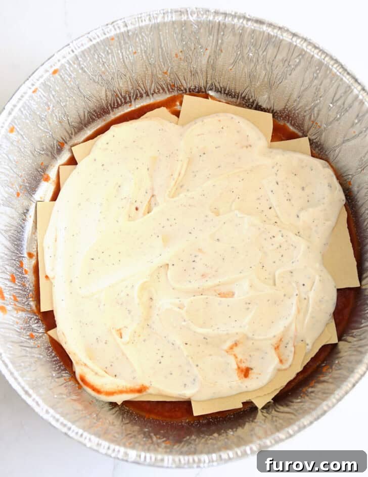 Ultimate Dutch Oven Lasagna 7 Top-down view of the creamy cottage cheese mixture spread over the lasagna noodles in the Dutch oven liner.
