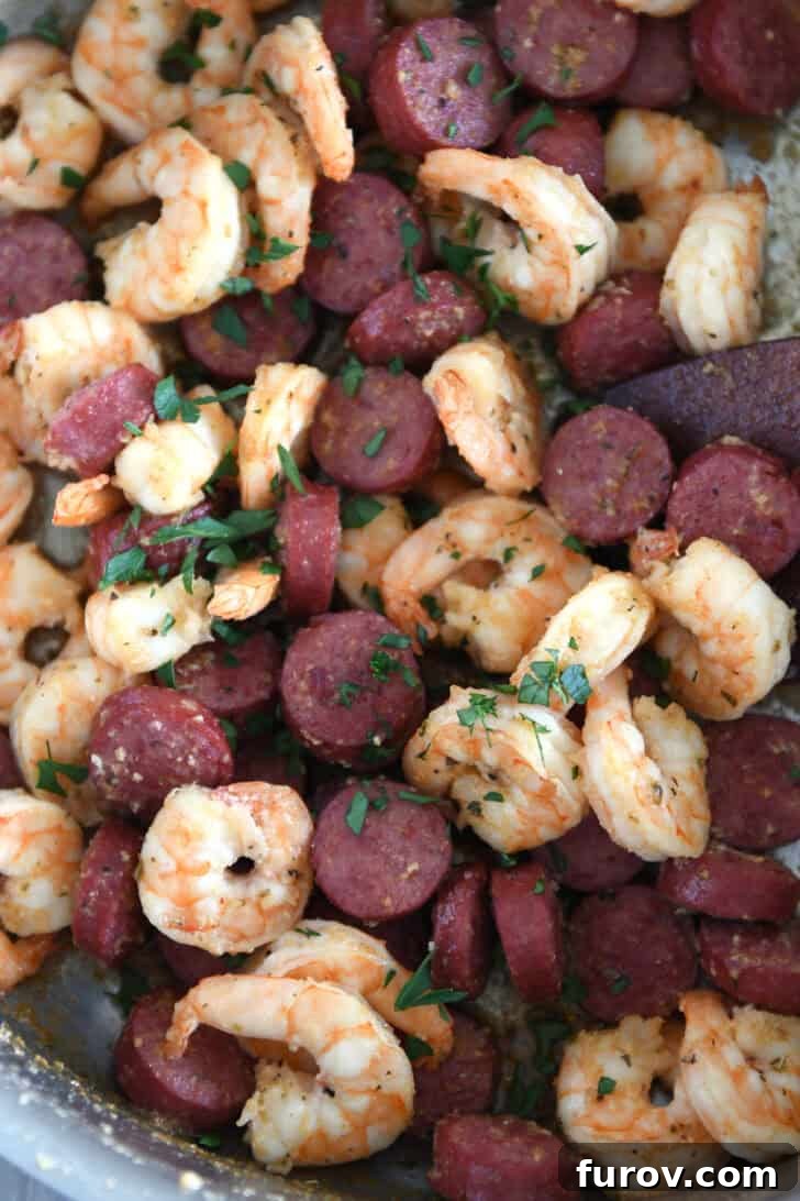 Garlic Butter Shrimp and Sausage Skillet 6 Generously loaded stainless steel skillet showcasing perfectly cooked shrimp and sausage, lightly sprinkled with fresh parsley.