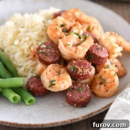 Gray plate with green beans, white rice, shrimp and sausage, a complete and flavorful meal.