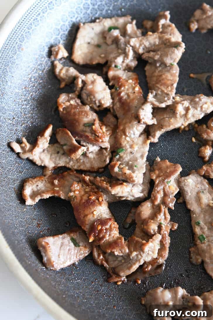Close-up of perfectly pan-seared pieces of bulgogi beef in a nonstick skillet, showing the beautiful caramelization achieved through proper cooking.