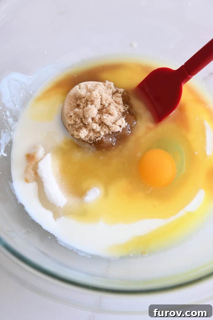 Spiced Apple Cinnamon Treats 3 Glass bowl containing brown sugar, granulated sugar, milk, and an egg, representing the wet ingredients for the muffin batter.