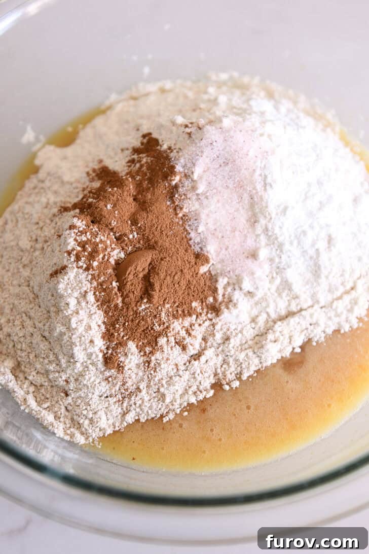 Spiced Apple Cinnamon Treats 4 Flour, whole wheat flour, cinnamon, and salt resting on top of the wet ingredients in a glass bowl, ready to be mixed.