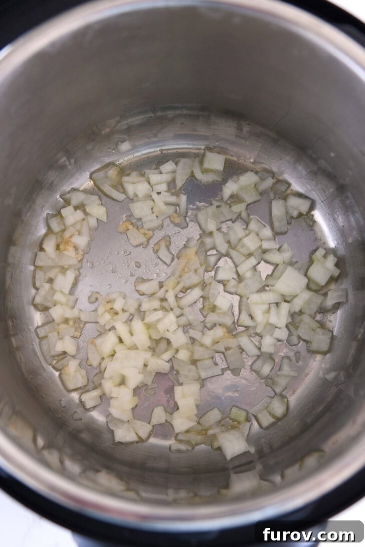 Top down view of Instant Pot with sauteed garlic and onions, forming the aromatic base of the soup.
