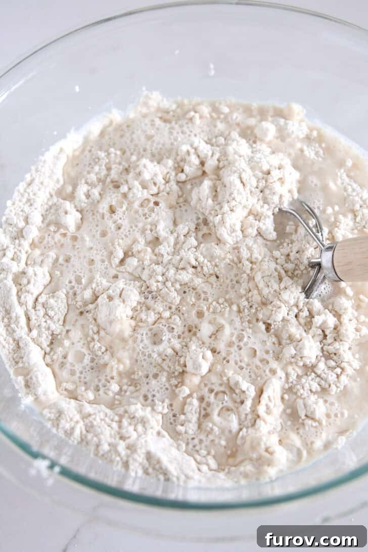 Glass bowl containing dry ingredients before mixing with water for cheesy peasant bread.