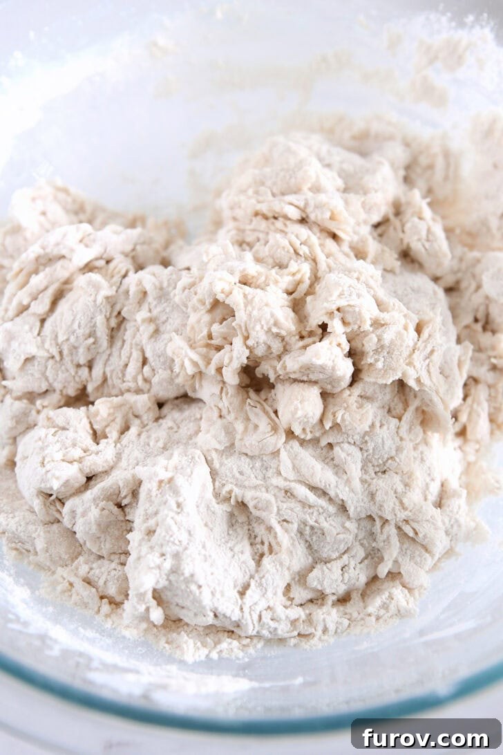 Shaggy bread dough after initial mixing in a glass bowl.