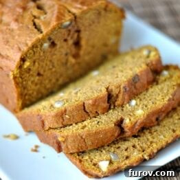 A top-down view of a single loaf of Pumpkin-Maple Hazelnut Bread, showcasing its golden-brown crust and a scattering of chopped hazelnuts on top.