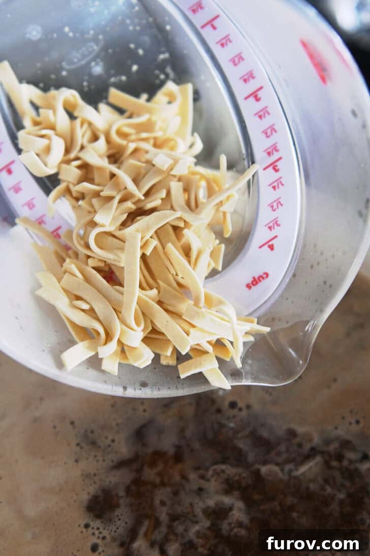 Pouring country-style noodles into a pot with beef broth.