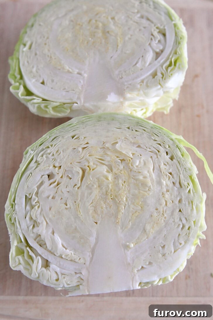 Two half green cabbages on wood cutting board.