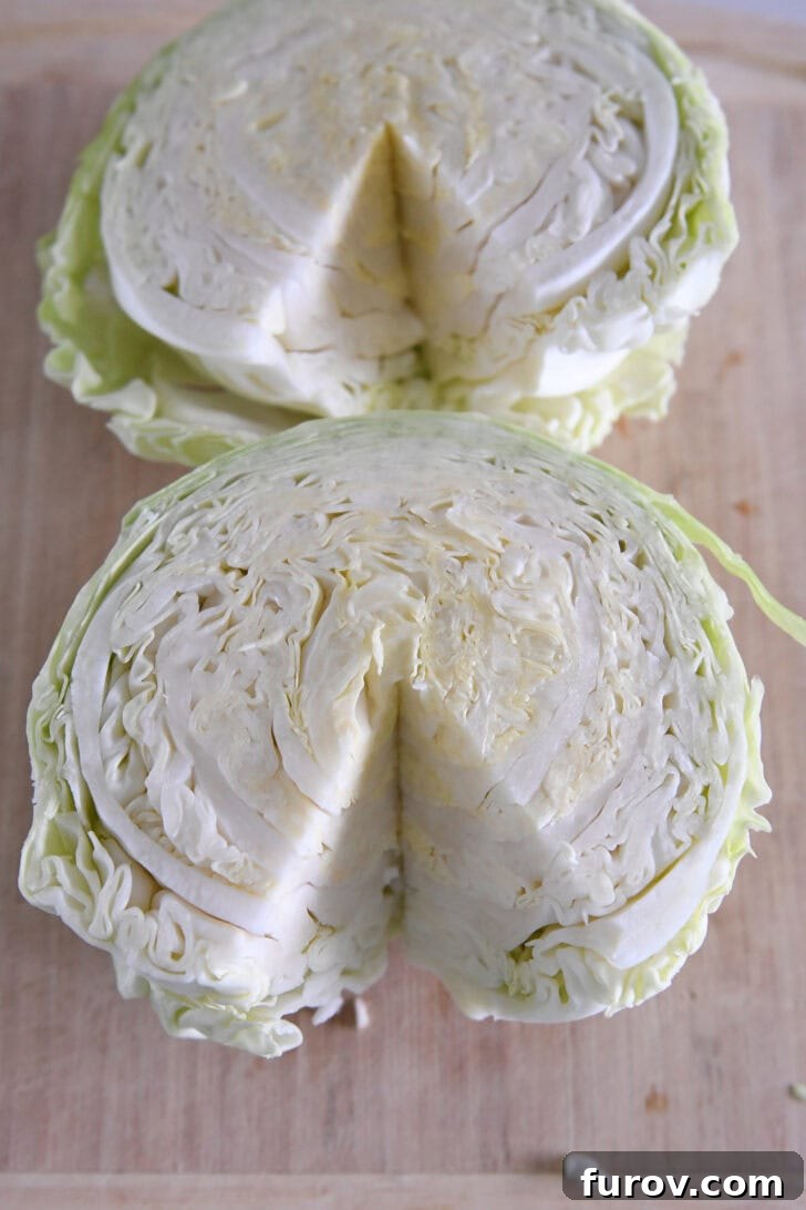 Two half green cabbages on wood cutting board with core removed.