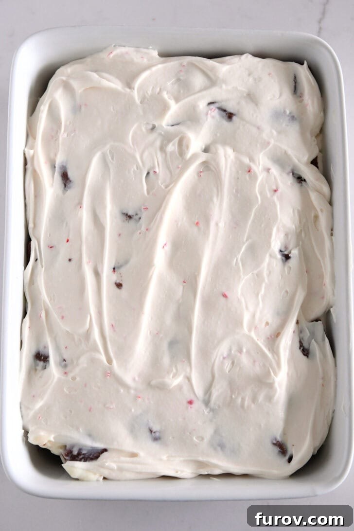 Peppermint cream cheese layer spread over the top of pudding in white baking dish.