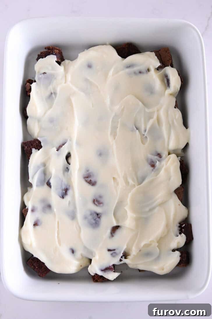 Pudding layer spread over top of brownie cubes in 9X13-inch white baking dish.