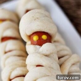 Mummy Dogs on a white platter with ketchup and mustard