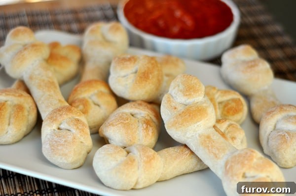 A white rectangular platter filled with golden-brown breadstick-shaped bones, perfect for a spooky Halloween meal.
