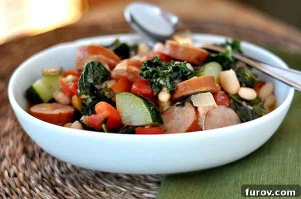Hearty Sausage and White Bean Ragout with Garden Vegetables 2 A comforting bowl of White Bean and Sausage Ragout, featuring wholesome white beans, sliced sausage, fresh kale, and tender zucchini, garnished with vibrant tomatoes.