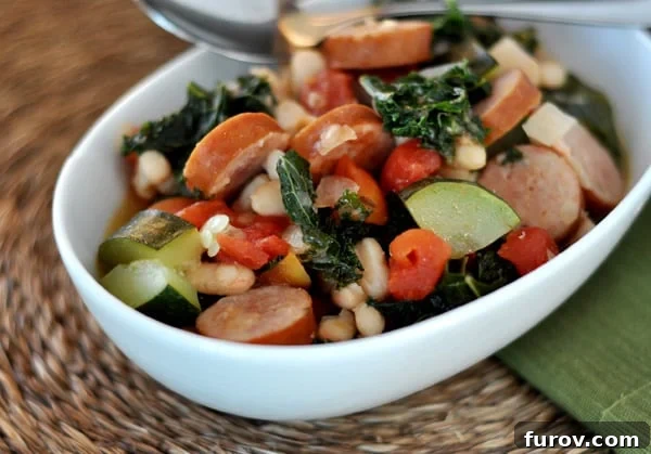 Hearty Sausage and White Bean Ragout with Garden Vegetables 3 An overhead shot revealing a steaming bowl of white bean and sausage ragout, showcasing the vibrant colors of kale, tomatoes, and zucchini mixed with savory sausage slices.