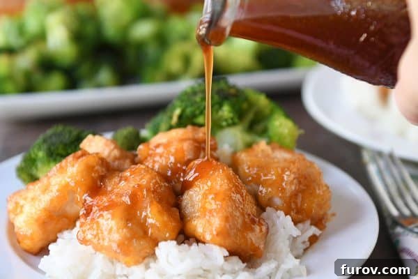 Tangy Honey Glazed Chicken 10 Baked sweet and sour chicken served over white rice on a clean white plate, with a drizzle of extra sauce.