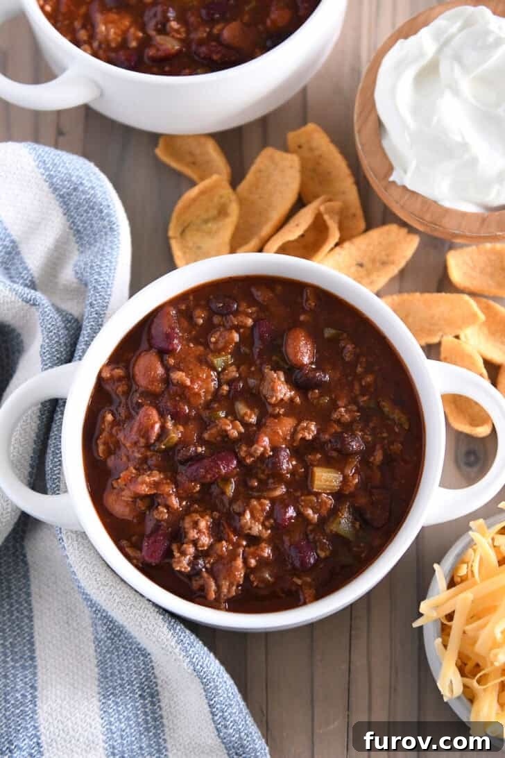 Top down view of southern beef and bean tomato chili in white bowl with handles.