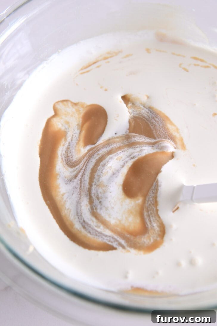 Caramel-Soaked Pumpkin Poke Cake with Whipped Caramel Topping 12 Glass bowl with the caramel cream cheese mixture, and heavy cream being poured in to create the whipped frosting.