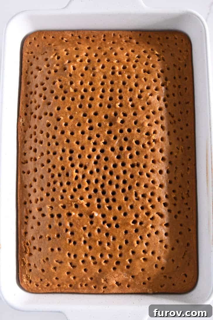 Caramel-Soaked Pumpkin Poke Cake with Whipped Caramel Topping 14 Top-down view of the pumpkin cake in a white 9x13-inch pan, covered with evenly spaced holes, ready for caramel infusion.