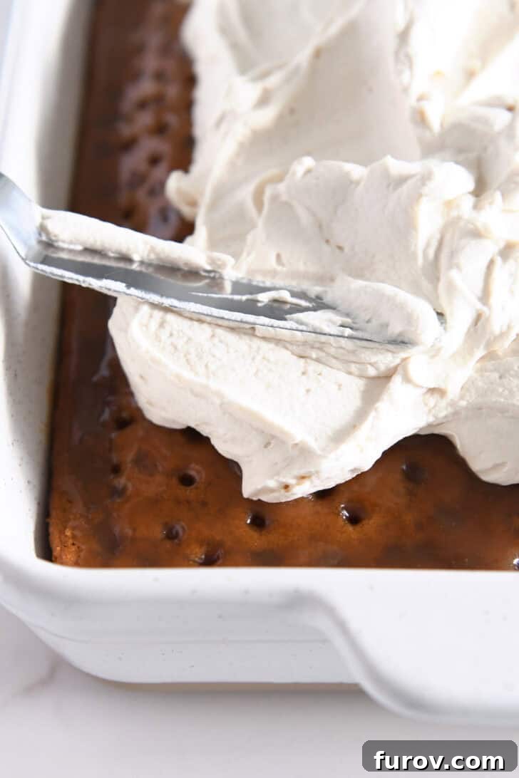 Caramel-Soaked Pumpkin Poke Cake with Whipped Caramel Topping 16 Spreading the luscious caramel cream frosting evenly over the top of the cooled caramel pumpkin poke cake.