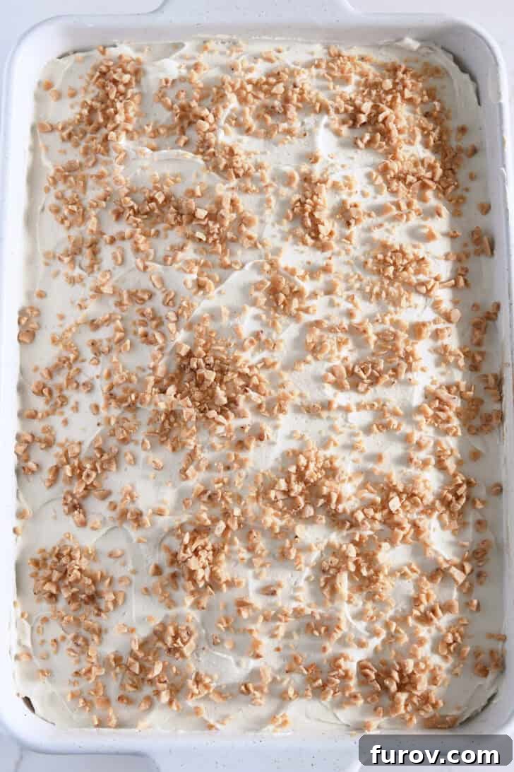 Caramel-Soaked Pumpkin Poke Cake with Whipped Caramel Topping 17 Top-down view of the fully assembled pumpkin caramel poke cake, crowned with whipped caramel cream frosting and a generous sprinkle of toffee bits.