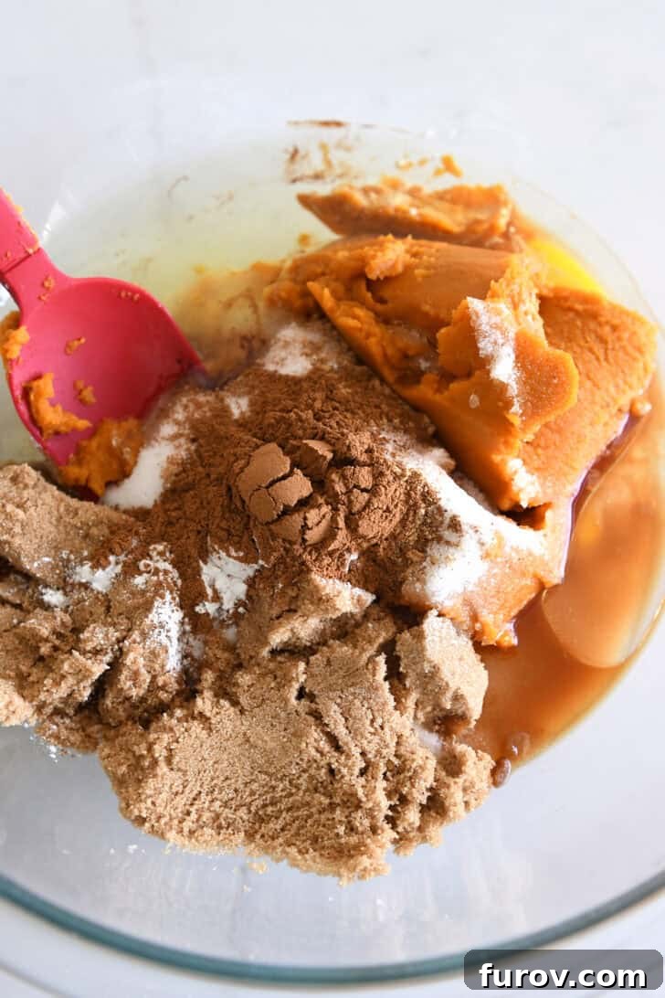 Caramel-Soaked Pumpkin Poke Cake with Whipped Caramel Topping 3 Glass bowl containing brown sugar, pumpkin puree, eggs, oil, cinnamon, and salt, ready to be whisked for pumpkin cake batter.