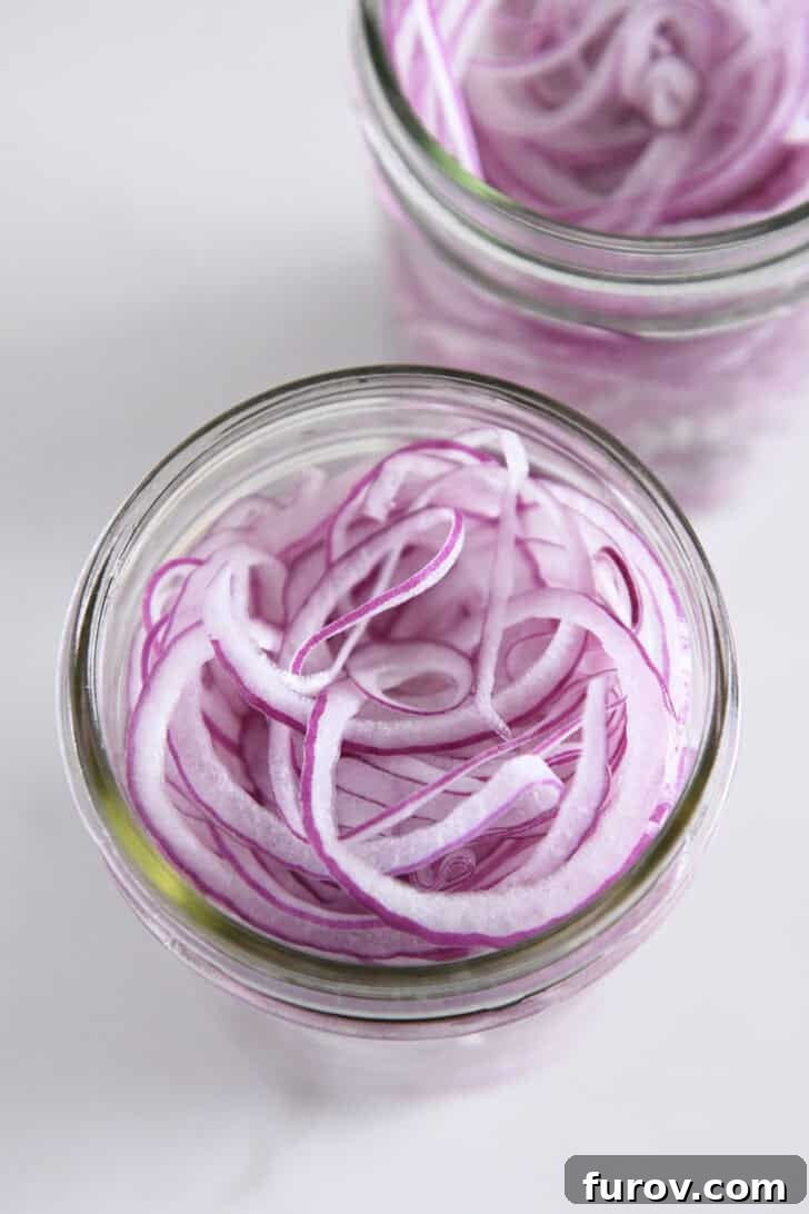 Top down view of pint jar with thinly sliced red onions.