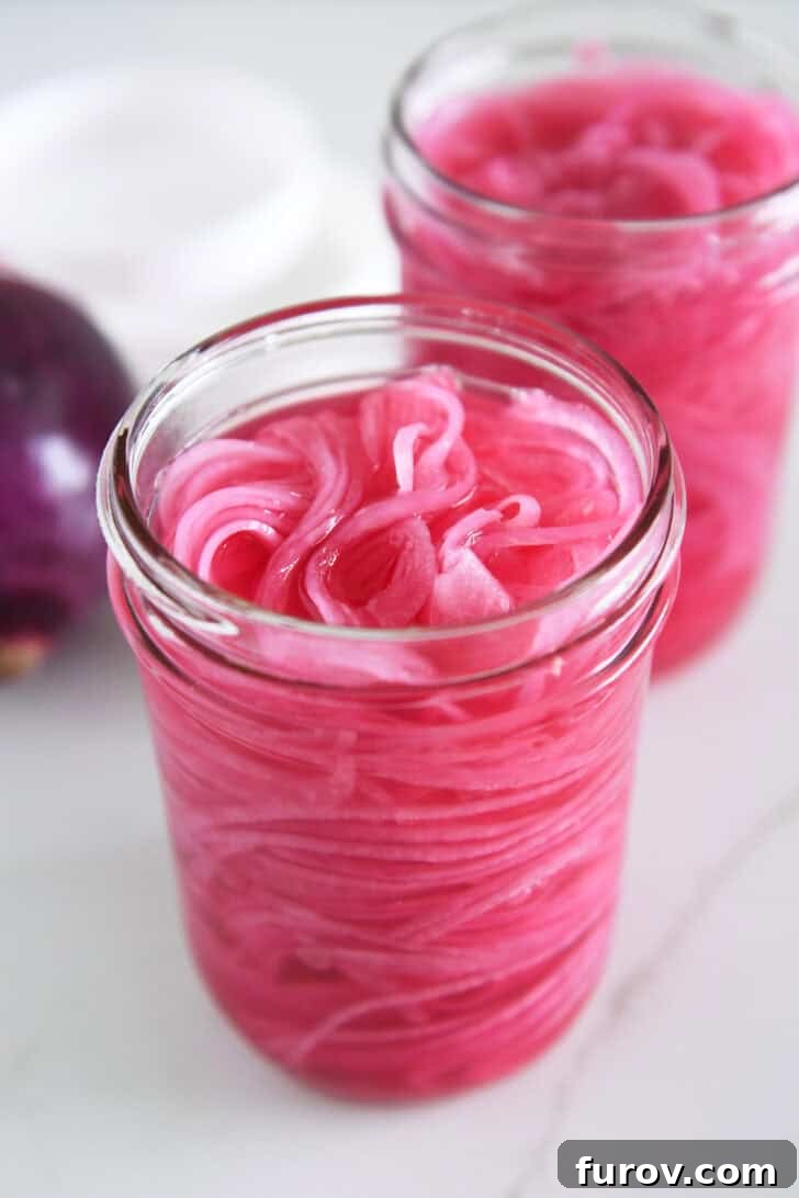 Two pint jars with thinly sliced red onions and vinegar.