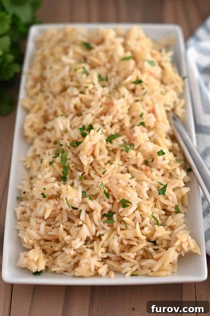 Top down view of rice pilaf with fresh parsley on white tray.