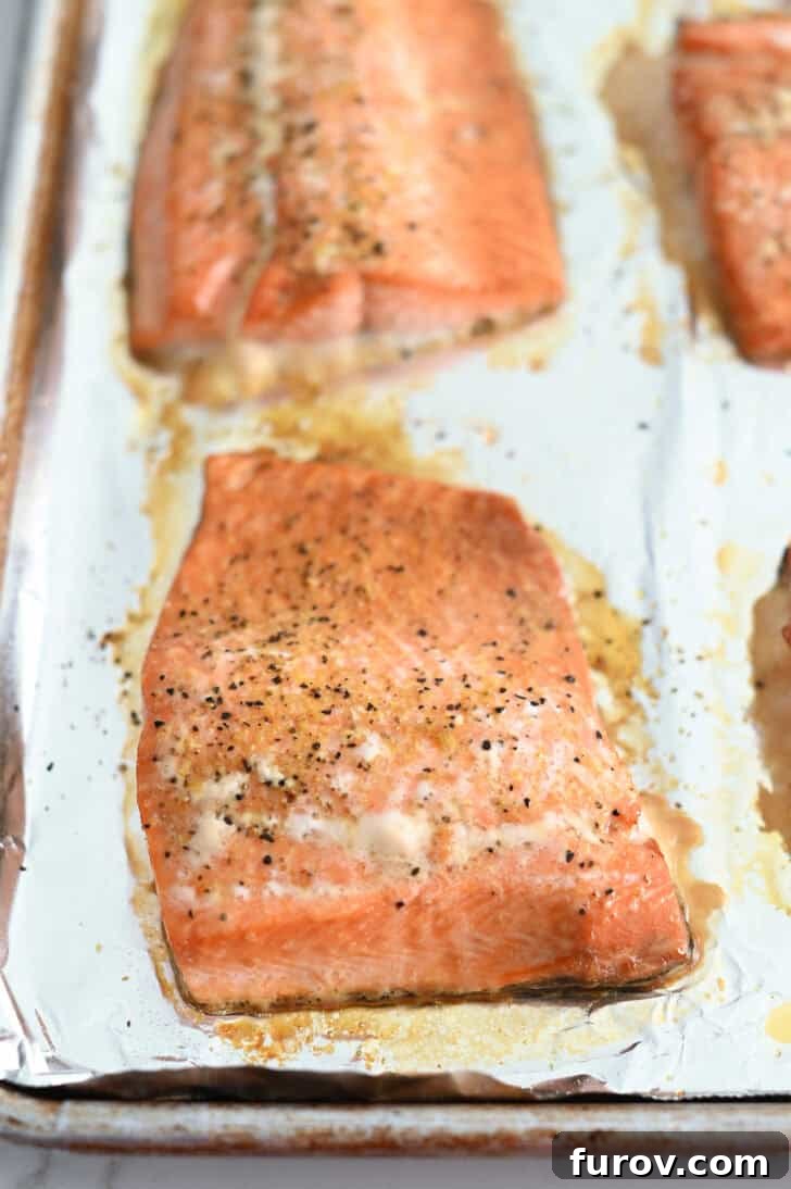 Perfectly baked salmon fillets, golden brown and flaky, resting on a foil-lined baking sheet fresh out of the oven.