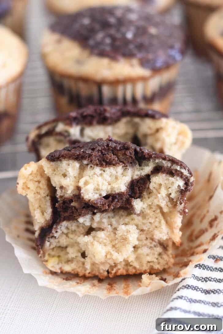 Marbled Chocolate Banana Muffins 13 A delectable banana muffin split in half, revealing the intricate chocolate ribbon swirl running beautifully through the moist, baked muffin.