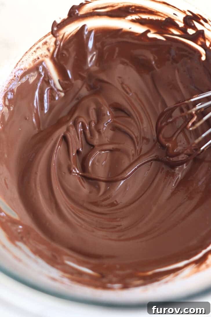 Marbled Chocolate Banana Muffins 5 A glass bowl containing a creamy, rich chocolate mixture being whisked, highlighting its smooth and consistent texture before being combined with banana batter.