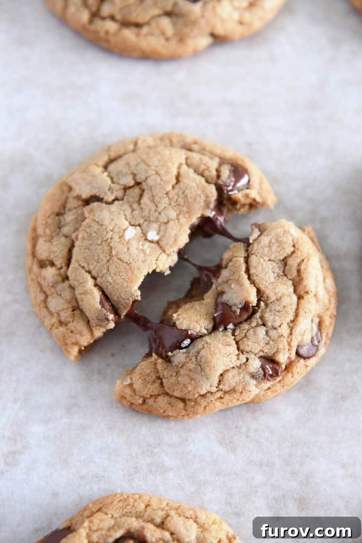 Top down view of a perfectly baked salted brown butter chocolate chip cookie pulled in half, revealing gooey, melty chocolate chips.