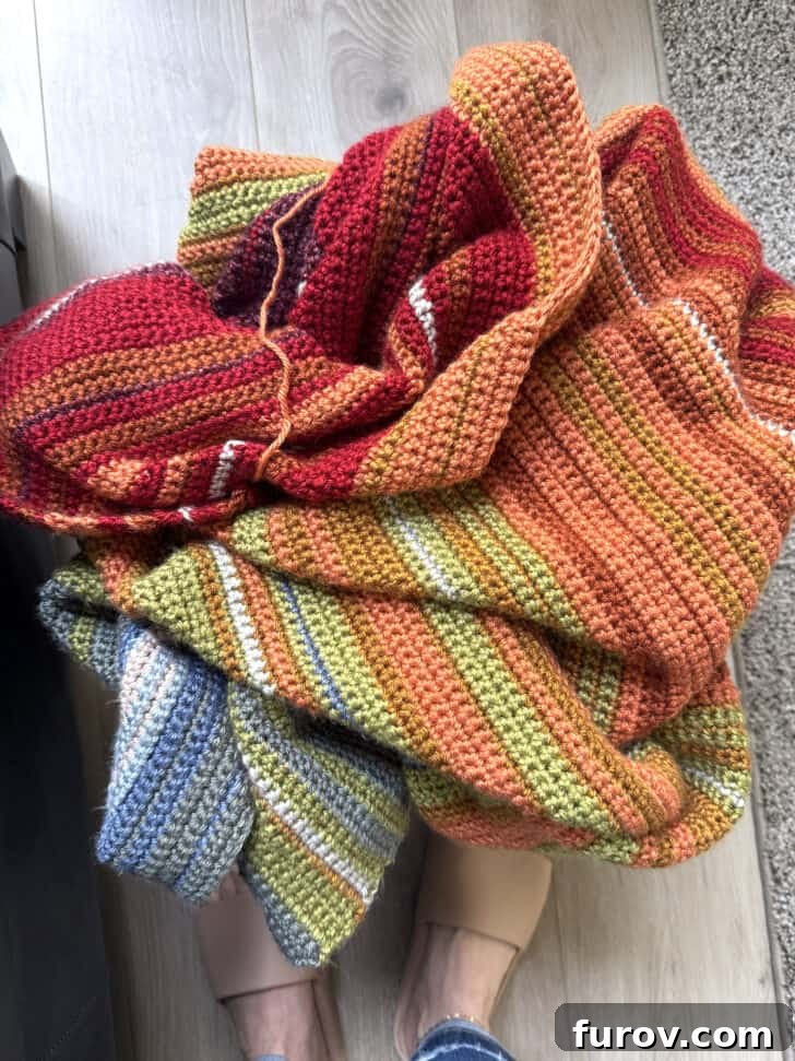 A beautifully crocheted temperature blanket, showcasing a spectrum of colors, piled neatly in a rustic basket.