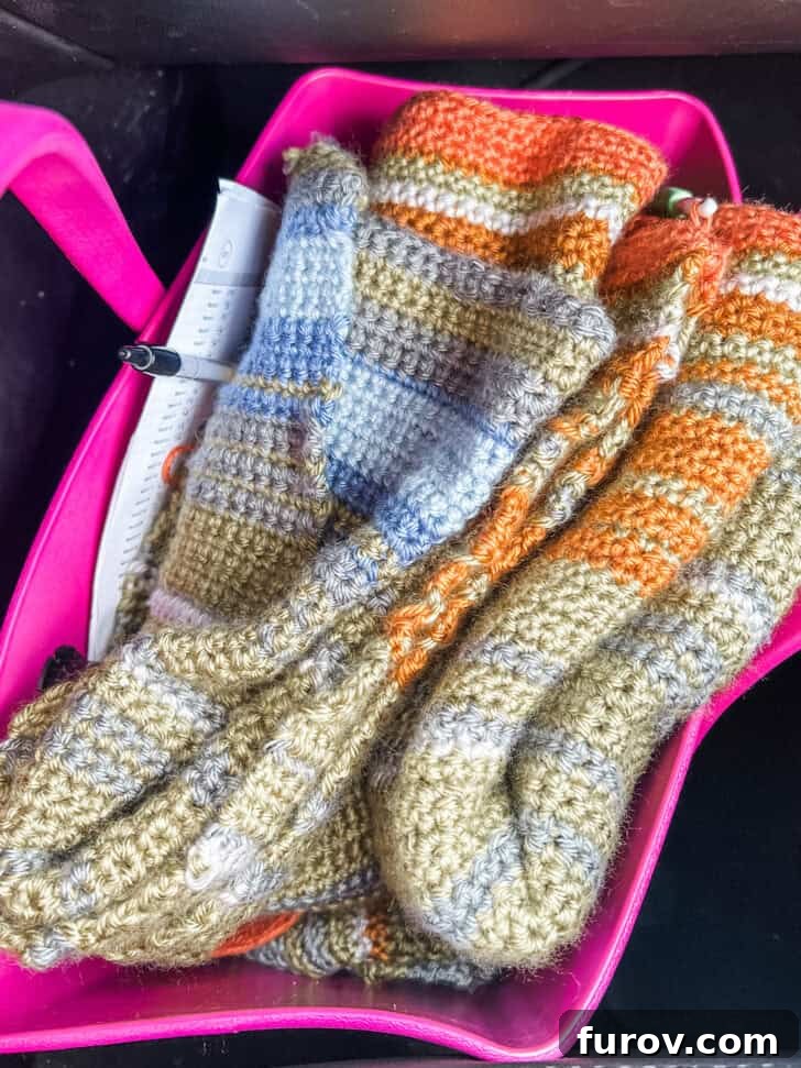 A large, colorful temperature blanket neatly folded and stuffed into a pink carrying bag, ready for travel.