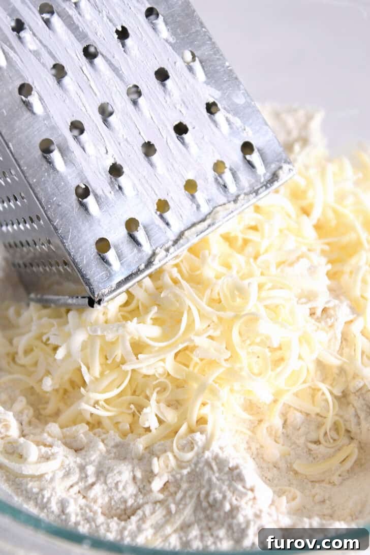 Finely grated cold butter shreds mixed into a bowl with dry ingredients, showcasing the perfect distribution for flaky scones.