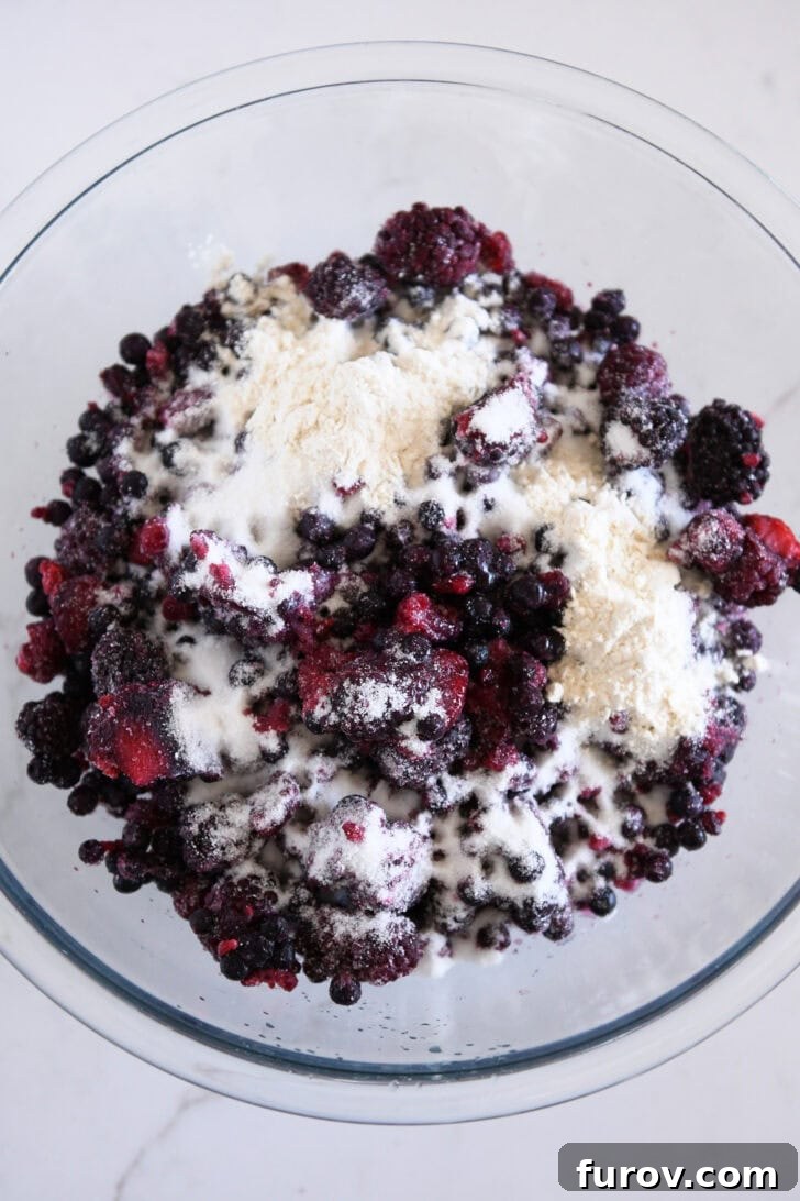 The Ultimate Triple Berry Cobbler with an Unforgettable Topping 3 A vibrant mix of fresh raspberries, blueberries, and blackberries in a clear glass bowl, ready to be prepared for baking the perfect cobbler.