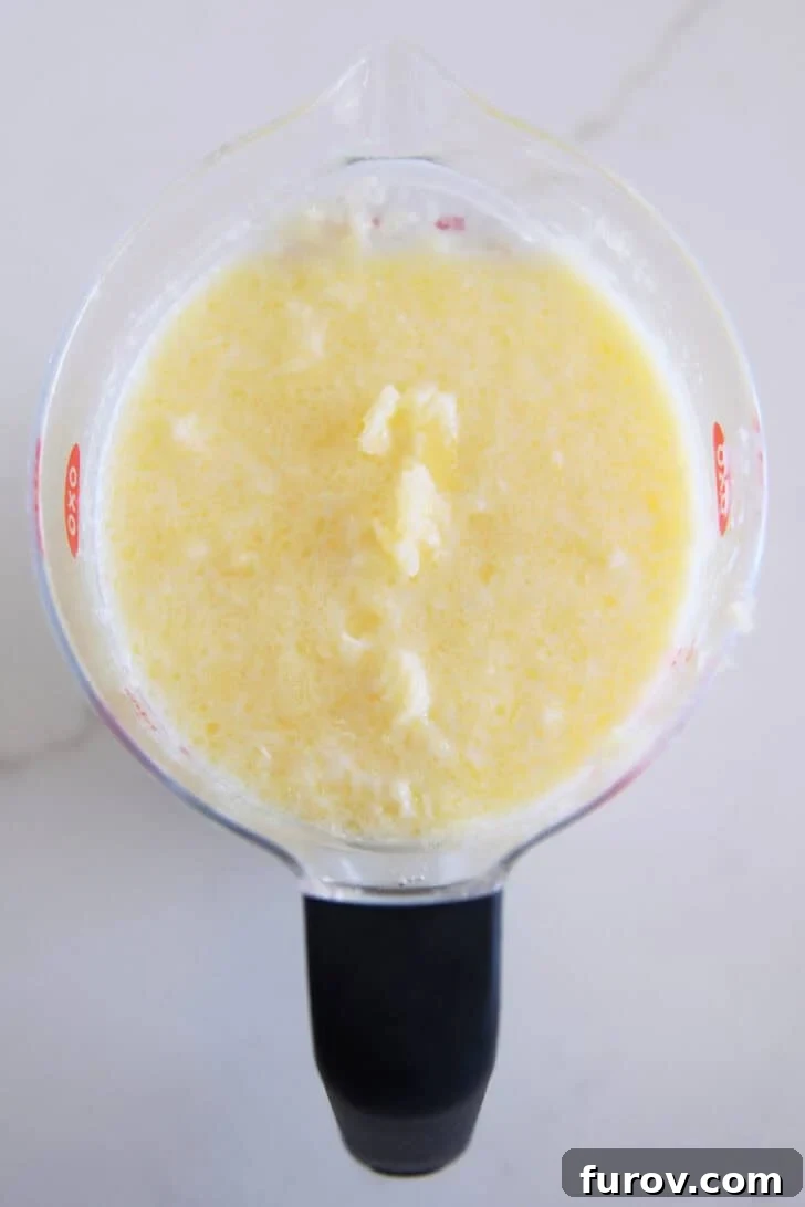 The Ultimate Triple Berry Cobbler with an Unforgettable Topping 5 Melted butter carefully poured into cold milk, creating small, beneficial clumps that are the secret to an incredibly tender cobbler topping, all captured in a liquid measuring cup.