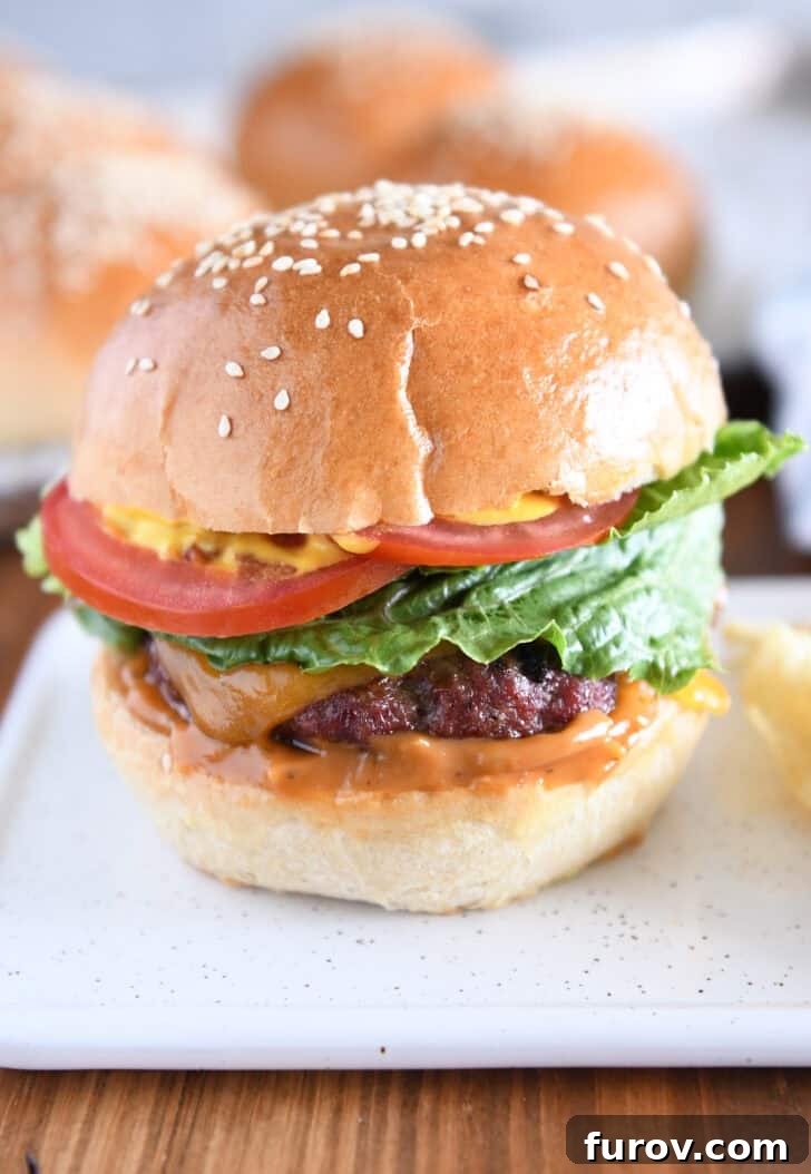 Homemade hamburger bun with juicy burger, lettuce, tomato and mustard.