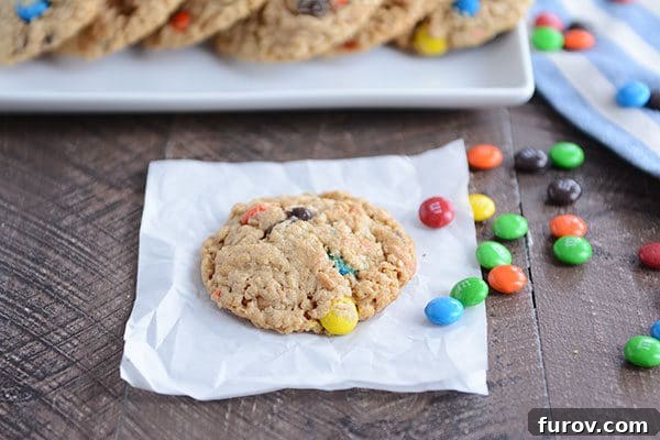 Epic One-Bowl Gluten-Free M&M Monster Cookies 6 A single, perfectly baked M&M cookie placed on a piece of parchment paper, with a few extra M&M's scattered delicately to the side.